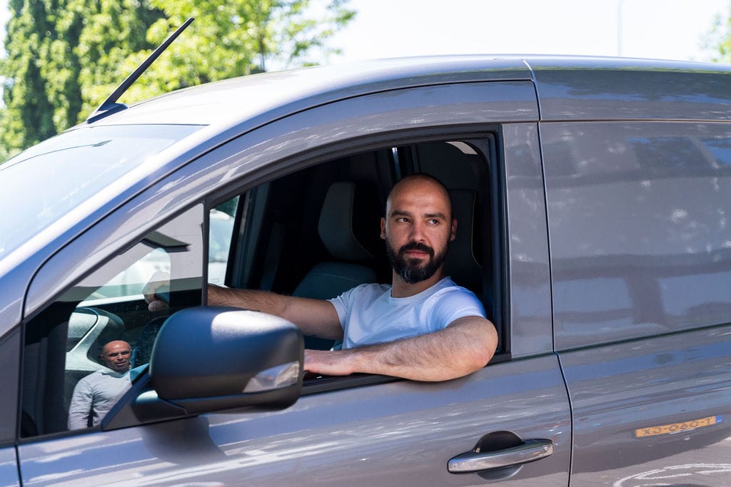 Man zit achter het stuur van een grijze bedrijfswagen, gefinancierd d.m.v. financial lease met negatieve BKR registratie